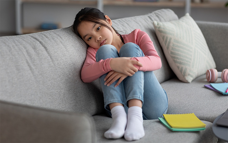 A sad child sitting on the couch